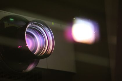 Close-up view of a projector lens with light reflections.