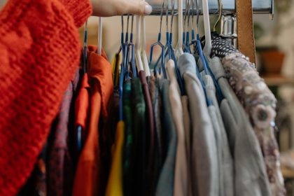 A woman browsing garments on hangers in a retail clothing store