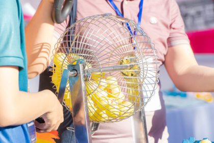 Two people engaging in a bingo game, spinning a cage.
