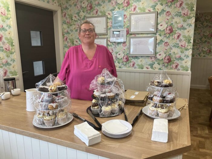 Avocet House team member standing behind homemade afternoon tea platters prepared for a community appreciation event.