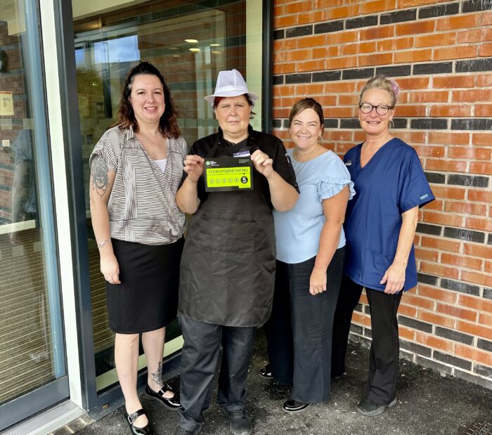 Beeston Rise team members proudly display the home's 5-star food hygiene rating certificate outside the care home.