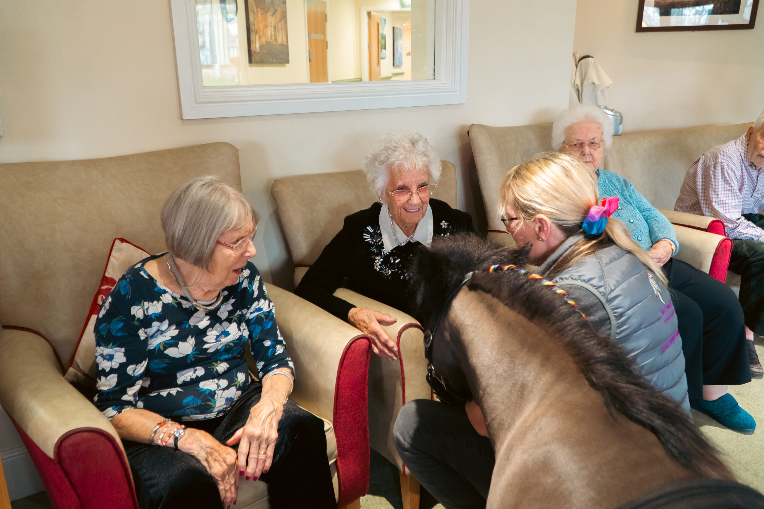 Two residents at Cloverleaf Care Home interacting with a Shetland pony during a therapy session.