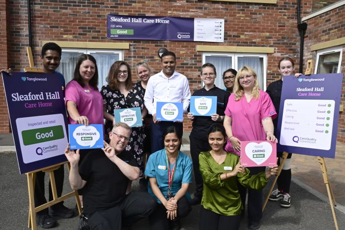 Staff members at Sleaford Hall Care Home standing outside the building holding signs for each CQC category rated Good, including Safe, Effective, Caring, Responsive, and Well-Led.