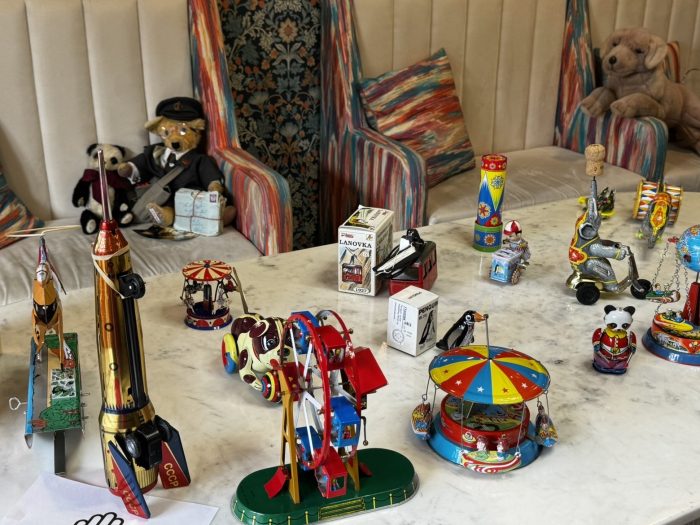 A wide display of vintage tin toys, including a Ferris wheel, carousel, and tin rocket, laid out on a marble table at York Manor Care Home.