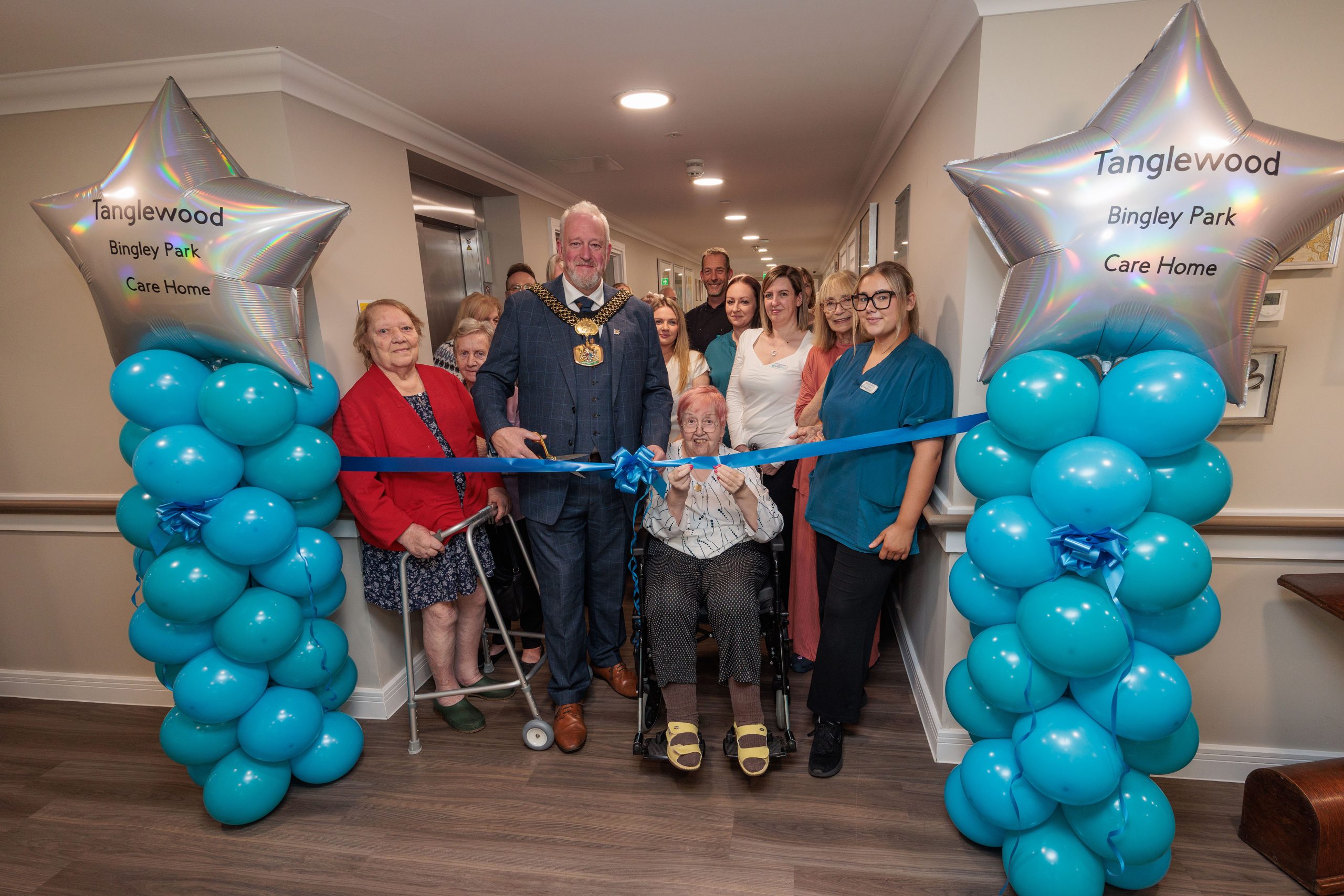 Lord Mayor of Bradford with residents and care team members gathered around the blue ribbon at Bingley Park's new dementia floor.